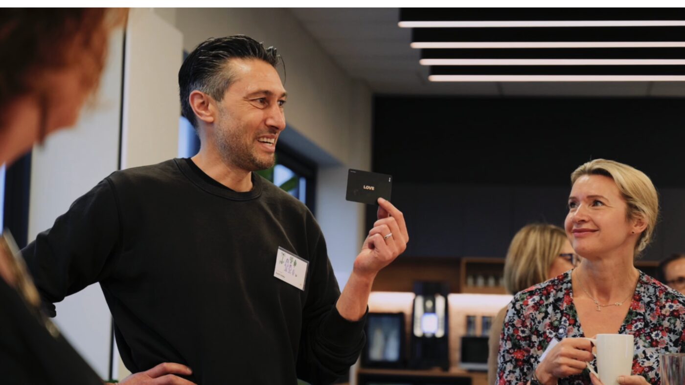 A riders&elephants community member holding up the LOVE card from the Emotional Culture Deck, mid-conversation with a colleague